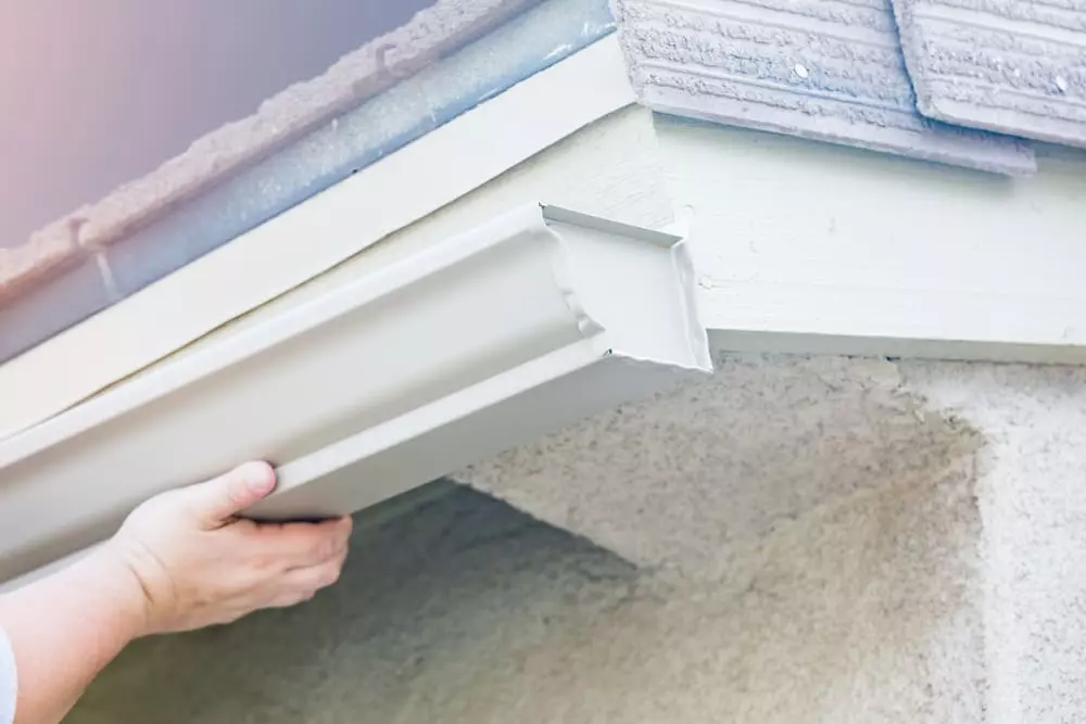 worker installing new aluminum gutters