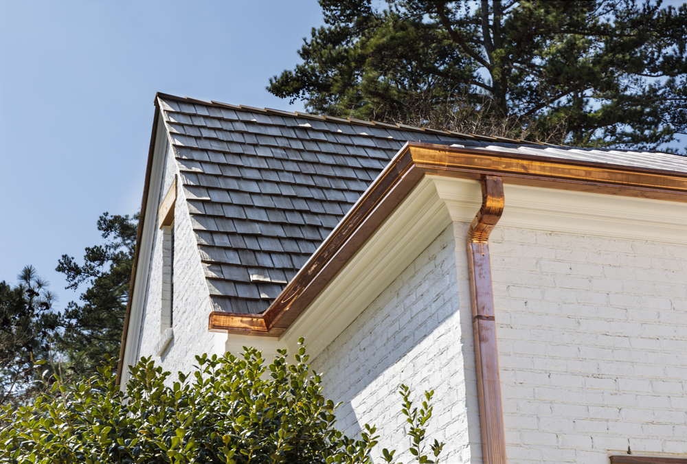 shiny copper gutters on white brick house