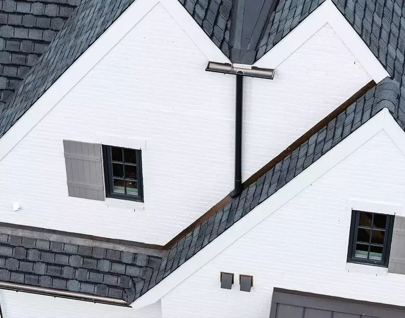 GutterPro's black half-round gutter system is installed on this white brick home to deliver a perfect blend of modern style and effective drainage.