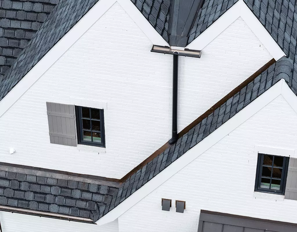 GutterPro's black half-round gutter system is installed on this white brick home to deliver a perfect blend of modern style and effective drainage.