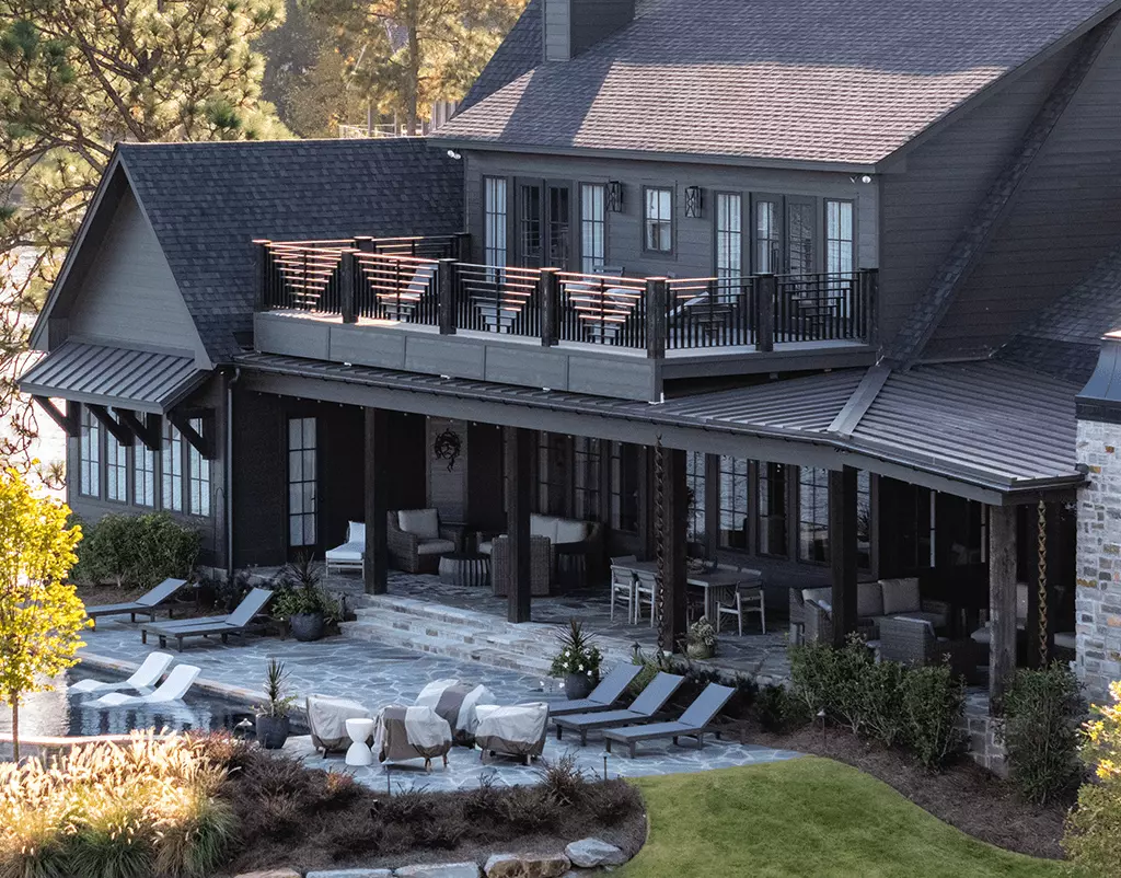 Sleek, black half-round gutters from GutterPro on wooden home facade that sits on the lakeside.