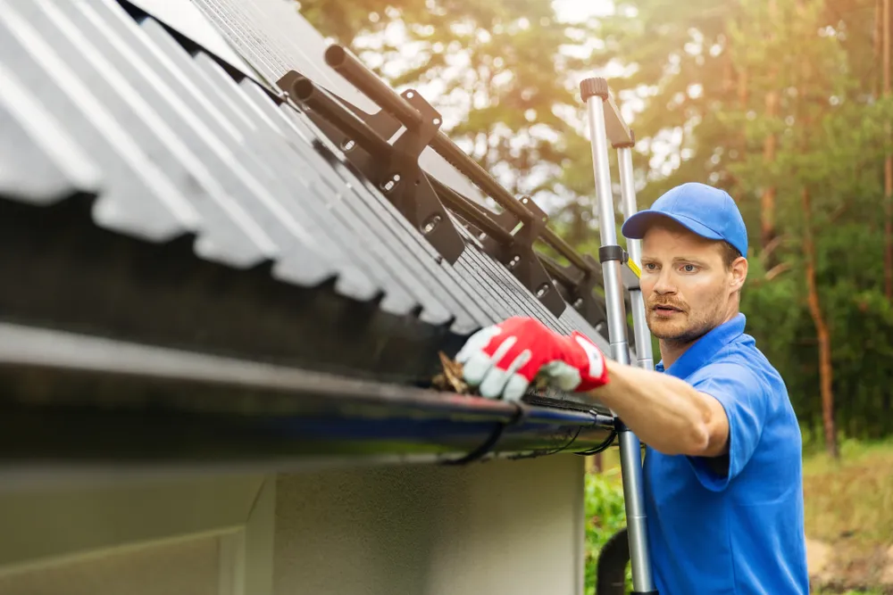 professional on ladder cleaning out gutter