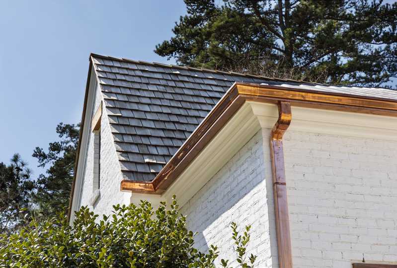 shiny copper gutters on white brick house