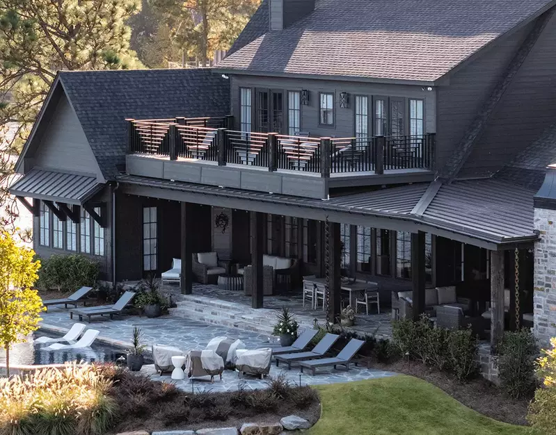 Sleek, black half-round gutters from GutterPro on wooden home facade that sits on the lakeside.